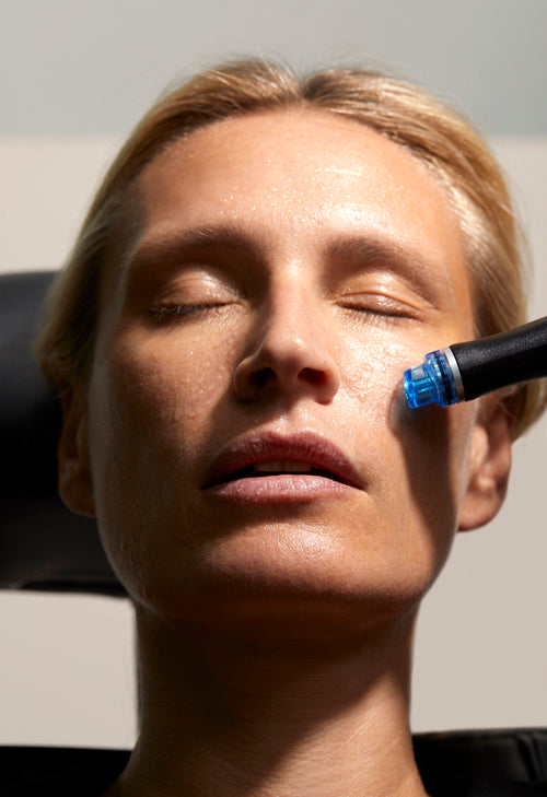 Une femme blonde reçoit un soin HydraFacial dans un centre de médecine esthétique.