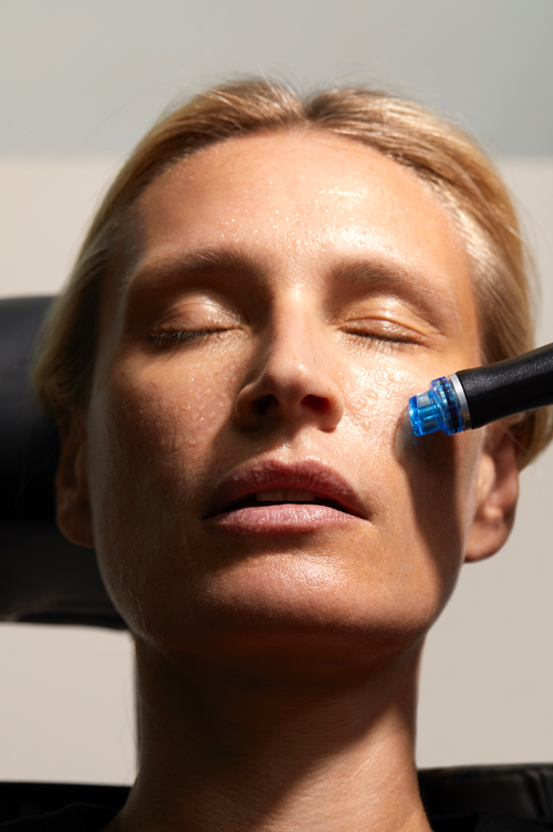 Une femme blonde reçoit un soin HydraFacial dans un centre de médecine esthétique.