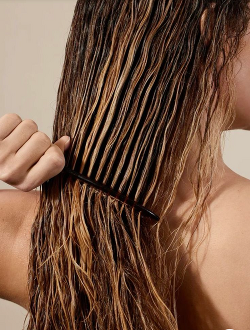 Une femme prend soin de ses cheveux en les peignant.